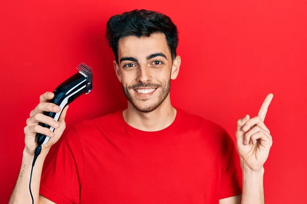 Joven Hombre Hispano Cargando Máquina Afeitar Eléctrica Sonriendo Feliz Señalando —  Fotos de Stock