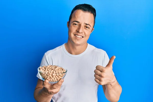 Bonito Jovem Segurando Tigela Grão Bico Sorrindo Feliz Positivo Polegar — Fotografia de Stock