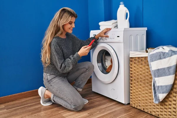 Ung Blond Kvinna Med Smartphone Väntar Tvättmaskin Tvättstugan — Stockfoto