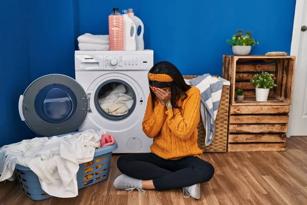 泣きながら手で顔を覆う悲しい表情で洗濯をしている若いヒスパニック系の女性 うつ病の概念 — ストック写真
