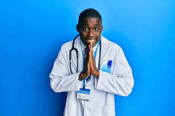 Jovem Afro Americano Vestindo Uniforme Médico Rezando Com Mãos Juntas — Fotografia de Stock