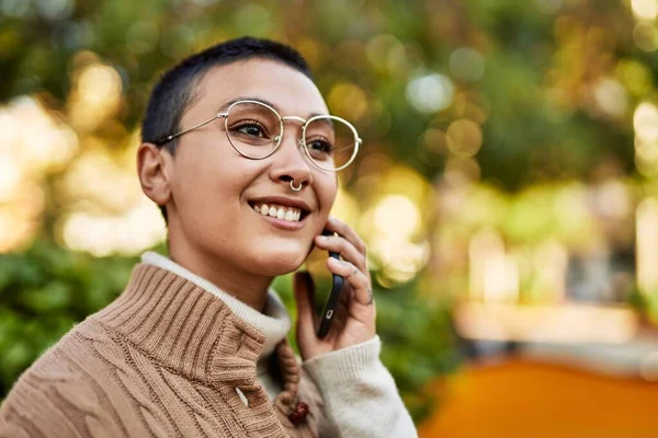 Kısa saçlı, gülümseyen, telefonda konuşan genç İspanyol kadın.