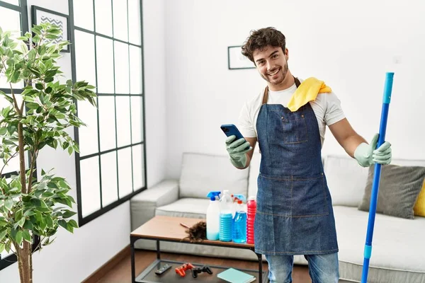 Joven Hispano Sonriendo Confiado Limpiando Usando Smartphone Casa — Foto de Stock