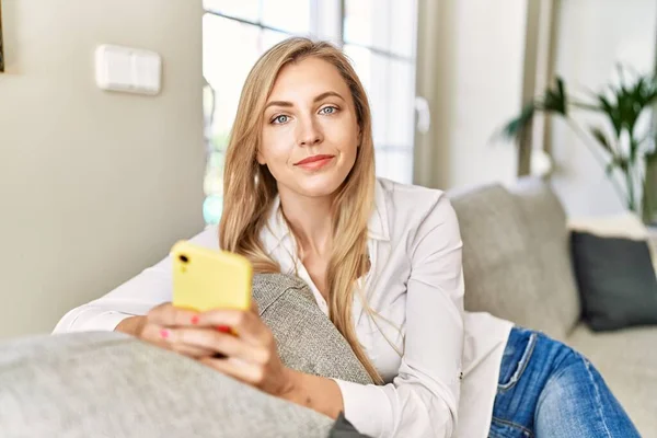 Ung Blond Kvinna Med Smartphone Sitter Soffan Hemma — Stockfoto