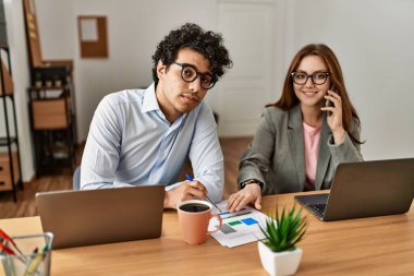 İki iş adamı çalışırken mutlu bir şekilde gülümsüyor ve ofisteki akıllı telefondan konuşuyor..