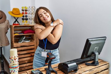 Genç esmer bir kadın perakende dükkanında açık mesajla pankart tutuyor mutlu ve olumlu bir şekilde kendine sarılıyor, kendinden emin gülümsüyor. Sevgi ve özgüven. 