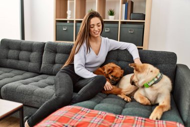 Kanepede oturmuş köpeklerle gülümseyen İspanyol bir kadın.