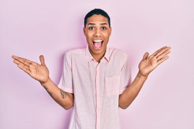 Genç Afro-Amerikan adam gündelik giysiler giyip zaferi mutlu bir gülümsemeyle kutluyor ve kazanan el kaldırıyor. 