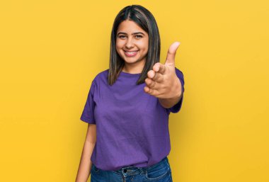 Latin kökenli genç bir kız, günlük mor tişört giyip dostça bir şekilde el sıkışarak hoş geldin diyor. başarılı iş. 