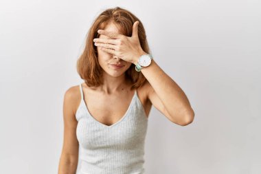 Güzel, beyaz bir kadın izole edilmiş arka planda duruyor. Elle gözlerini kapatıyor, ciddi ve üzgün görünüyor. Görme, saklama ve reddetme konsepti 