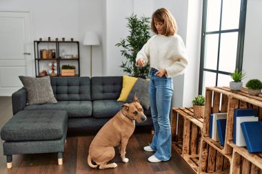 Genç, beyaz bir kadın köpeğini evde besliyor.