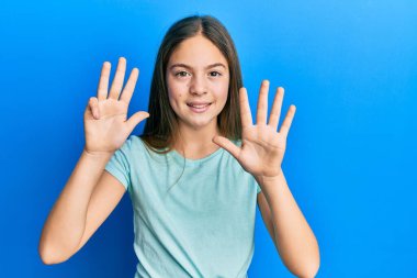 Güzel, esmer, beyaz tişört giyen küçük bir kız dokuz numaralı parmaklarıyla onu gösteriyor ve gülümsüyor. Kendinden emin ve mutlu.. 