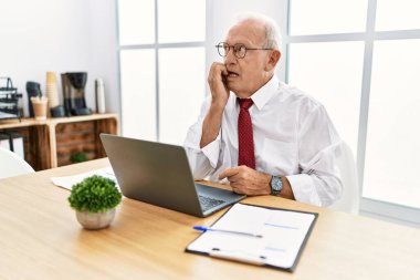 Ofiste çalışan üst düzey bir adam bilgisayar kullanıyor. Stresli ve gergin görünüyor. Elleri ağızdan tırnak yiyor. anksiyete. 