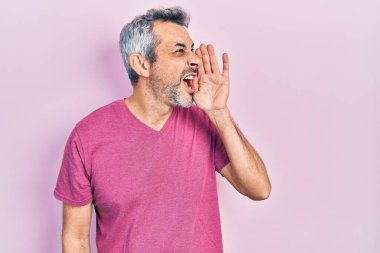Gri saçlı, sıradan pembe tişörtlü, eli ağızda bağırıp çağıran yakışıklı, orta yaşlı bir adam. iletişim konsepti. 