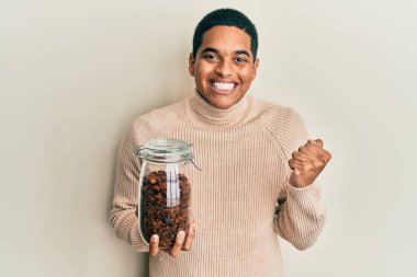 Genç, yakışıklı İspanyol adam elinde kuru üzümlerle dolu kavanozla gururla haykırıyor zaferi ve başarıyı kutluyor. 