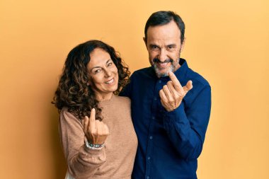 Orta yaşlı İspanyol bir çift, sıradan kıyafetler giyip, el kol hareketi yaparak, mutlu bir şekilde karşılamaya ve gülümsemeye geliyorlar. 