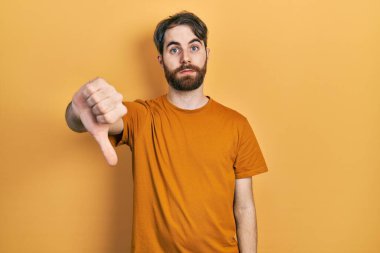 Sakallı, sıradan sarı tişörtlü, mutsuz görünen, reddedilmiş ve olumsuz jestli beyaz bir adam. kötü ifade. 