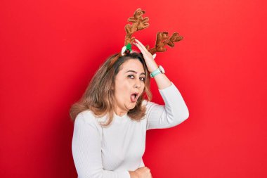 Orta yaşlı, beyaz, şirin Noel geyiği boynuzları takan bir kadın. Yanlışlıkla el ele tutuşan boynuzlar. Hatayı hatırla. Unuttum, kötü hafıza kavramı. 