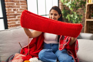 Genç İspanyol kadın gülümsüyor. Elinde ev yapımı bir eşarp tutuyor.