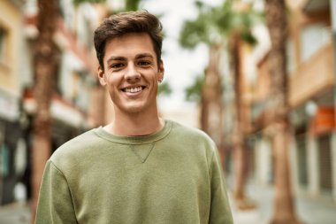 Genç İspanyol adam gülümseyerek şehirde mutlu mesut dikiliyor..