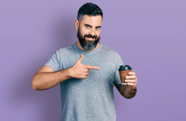 Sakallı, İspanyol bir adam bir fincan kahve içiyor. Gülümsüyor, eli ve parmağı ile işaret ediyor. 