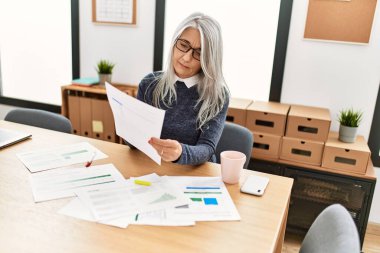 Ofiste çalışırken gülümseyen beyaz saçlı iş kadını.