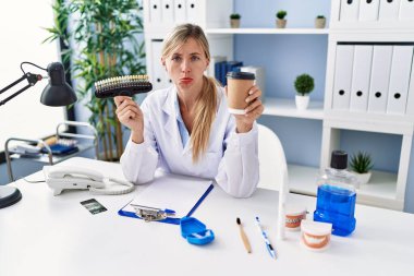 Diş macunu ve diş fırçası tutan güzel bir dişçi kadın. Depresyonda ve endişe içinde, kızgın ve korkmuş bir şekilde ağlıyor. hüzünlü ifade. 