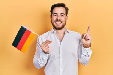 Handsome caucasian man with beard holding germany flag smiling happy pointing with hand and finger to the side 