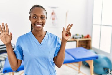 Saçları örgülü zenci bir kadın ağrı kesici kliniğinde çalışıyor. Sekiz numaralı parmaklarıyla işaret ediyor ve gülümsüyor. Kendinden emin ve mutlu.. 