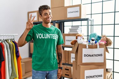 Bağışlarda gönüllü tişört giyen yakışıklı İspanyol adam kameraya bakıp zafer işareti yaparken gülümsüyor. İki numara.. 