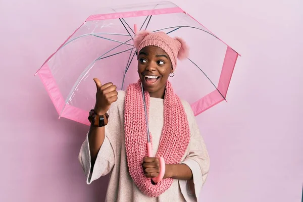 Joven Mujer Afroamericana Sosteniendo Paraguas Apuntando Con Pulgar Hacia Lado —  Fotos de Stock