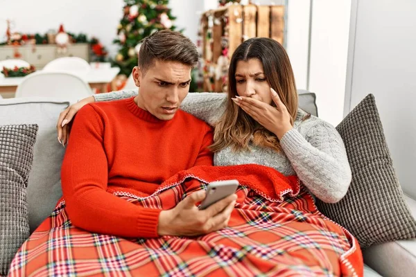 Young Hispanic Couple Sitting Sofa Christmas Covering Mouth Hand Shocked — Stok fotoğraf