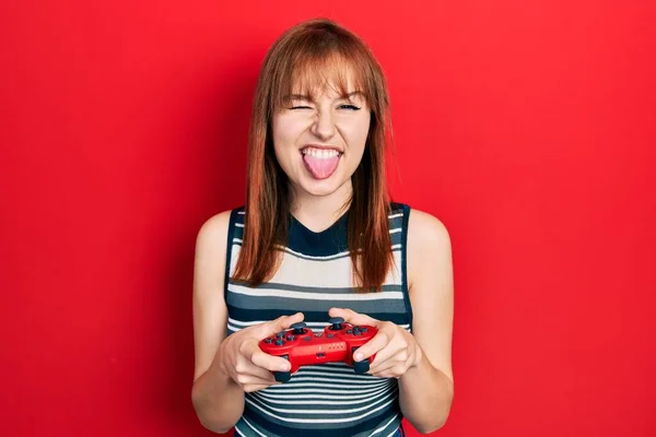 赤毛若いです女性再生ビデオゲームホールディングコントローラステッキング舌アウト幸せとともに面白い式 — ストック写真