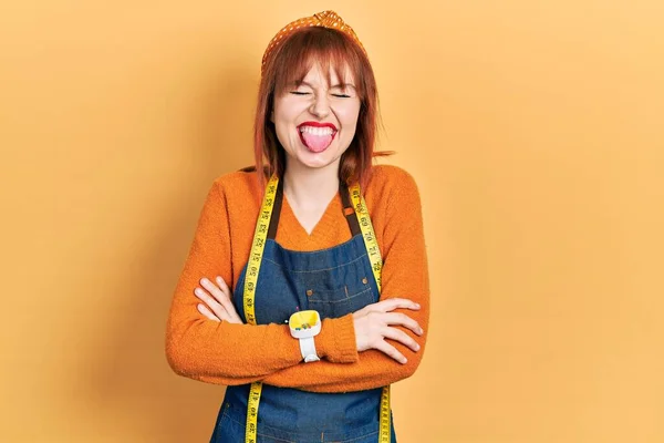 Redhead Young Woman Dressmaker Designer Wearing Atelier Apron Sticking Tongue — Stock Photo, Image