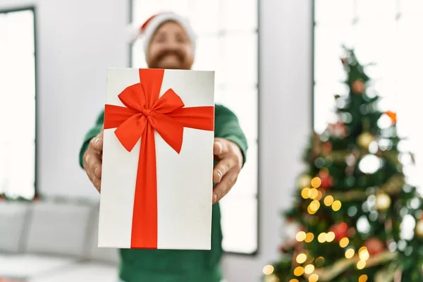 Young Redhead Man Holding Gift Standing Christmas Tree Home — Stock Photo, Image
