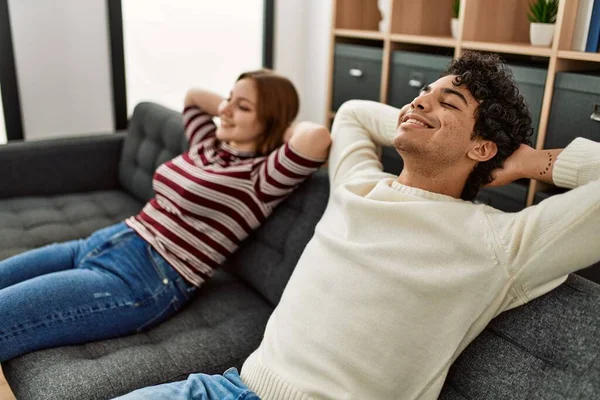 年轻夫妇高兴地微笑着 双手放在沙发上放松地呆在家里 — 图库照片