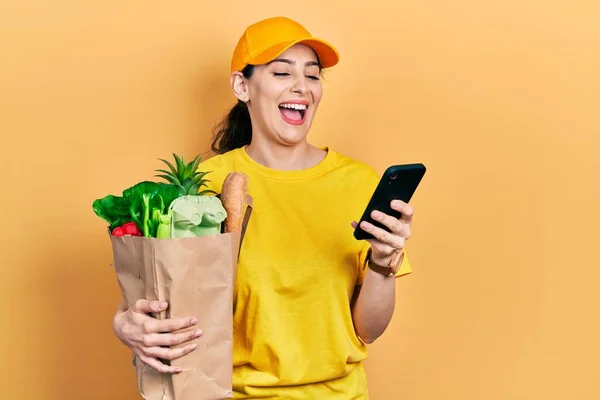 Ung Latinamerikansk Kvinna Håller Påse Med Livsmedel Med Smartphone Ler — Stockfoto