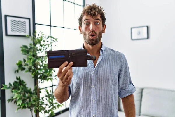 Joven Hombre Guapo Sosteniendo Cartera Cuero Asustado Sorprendido Con Boca —  Fotos de Stock