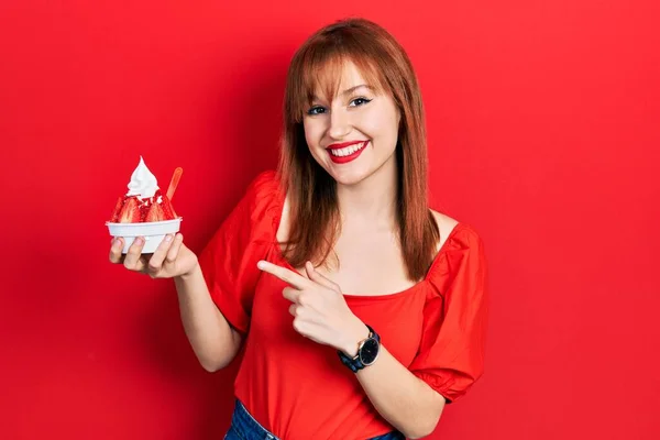 Κοκκινομάλλα Νεαρή Γυναίκα Κρατώντας Παγωτό Χαμογελώντας Χαρούμενη Δείχνοντας Χέρι Και — Φωτογραφία Αρχείου