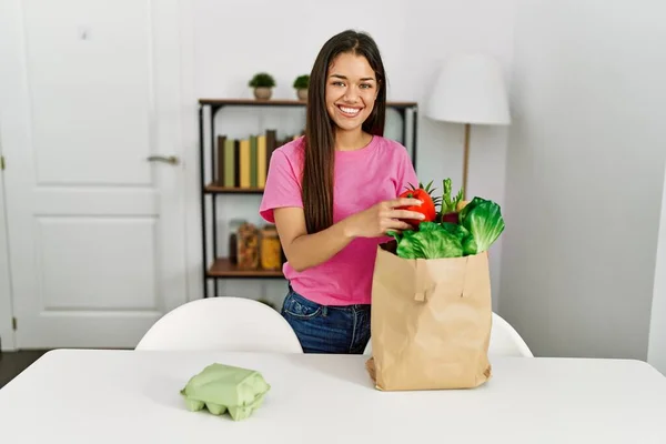 年轻的拉丁女人在家里拿着食品杂货袋 — 图库照片