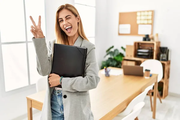 Ofisteki Sarışın Kadını Kameraya Göz Kırparak Gülümsüyor Parmaklarıyla Zafer Işareti — Stok fotoğraf
