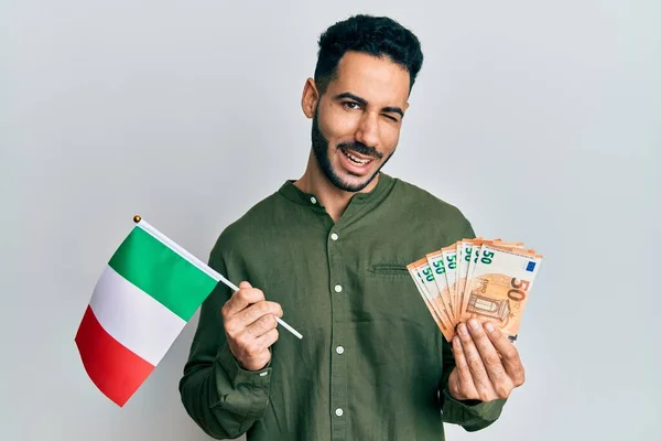 Junger Hispanischer Mann Mit Italienischer Flagge Und Euro Banknoten Zwinkert — Stockfoto