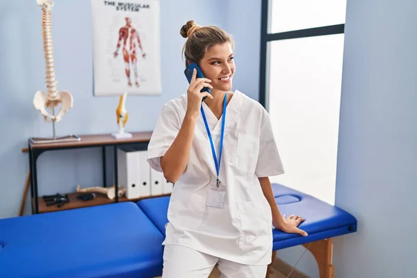 Mladá Blondýna Žena Uniformě Fyzioterapeuta Mluvit Smartphone Klinice — Stock fotografie