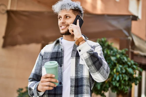 Genç İspanyol adam akıllı telefondan konuşuyor. Şehirde kahve içiyor..