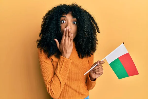 アフロヘアのアフリカ系アメリカ人女性は マダガスカルの国旗を手で口を覆い 衝撃を与え 間違いを恐れている 驚きの表情 — ストック写真