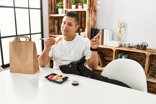 箸を使って寿司を食べる若いヒスパニック系の男は 側に手と指で笑顔幸せなポインティング — ストック写真