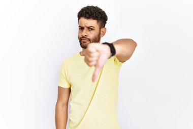 İzole edilmiş arka planda duran Arap genç adam mutsuz ve kızgın görünüyor. Reddedilmiş ve olumsuz bir hareket sergiliyor. kötü ifade. 