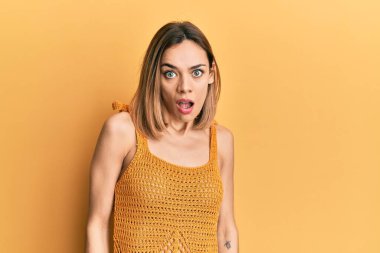 Şok suratlı, sıradan sarı tişört giyen, kuşkucu ve alaycı bakışlı, ağzı açık, şaşırmış genç, beyaz bir kadın. 
