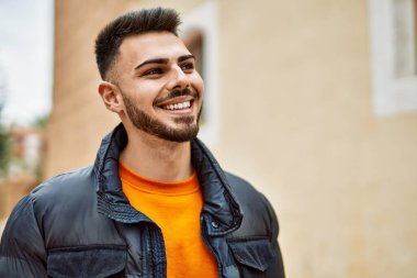 Yakışıklı, sakallı, neşeli ve kendine güvenen, kışlık palto giyen bir İspanyol.