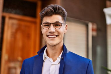 Sokakta kendine güvenen takım elbiseli ve gözlüklü bir genç.